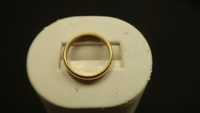 une bague en or posée sur un objet blanc