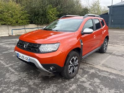 La Dacia orange est garée sur le parking.