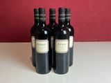 three bottles of wine sitting on a table in front of a red wall