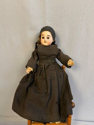 une poupée assise sur une chaise en bois
