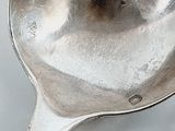 a silver spoon with a handle on a white surface
