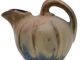 a brown and blue vase with a handle on a white surface