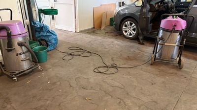 une voiture garée dans un garage, avec un aspirateur posé par terre