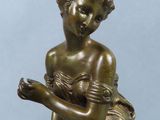 bronze statue of a young girl sitting on a rock with her hands in her lap