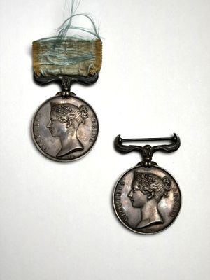 deux médailles d'argent ornées d'un ruban, posées sur un fond blanc