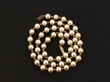 a gold pearl necklace on a black background