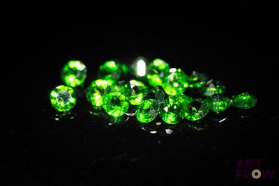 a pile of green diamonds on a black surface