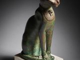 a statue of a cat sitting on top of a marble block