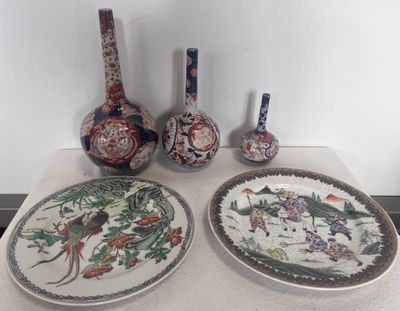 trois assiettes et deux vases posés sur une table