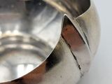 a silver bowl on a white surface with a brown stripe