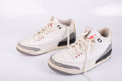 une paire de baskets blanches avec des touches de noir et de rouge sur fond blanc