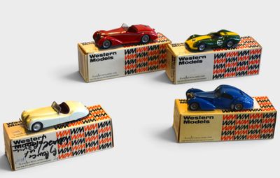 four toy cars are sitting on top of boxes on a white surface