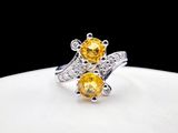 a close up of a ring with two yellow stones on it