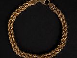 un bracelet en or en forme de corde avec un fermoir, sur fond noir