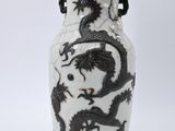 un vase blanc orné de motifs représentant des dragons noirs