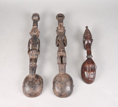 trois figurines en bois de formes et de tailles différentes posées sur une surface blanche