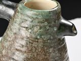 a close up of a vase with a handle on a table