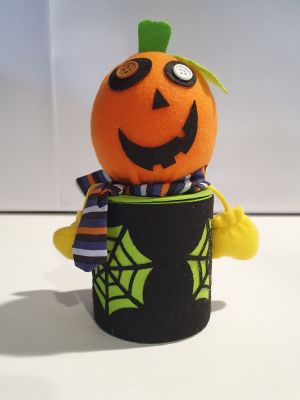 une citrouille en peluche vêtue d'un t-shirt noir et d'un chapeau vert