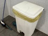 a white trash can and a mop in a bathroom