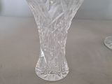 a clear glass vase sitting on a table next to a wine glass