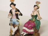 deux figurines d'un homme et d'une femme assis sur un rocher