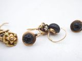 three pairs of gold and black stone earrings on a white surface