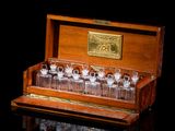 a wooden case with several glasses in it on a black surface