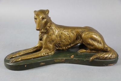 statue d'un chien doré couché sur un socle vert