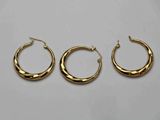 trois paires de boucles d'oreilles créoles en or sur fond blanc