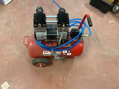a small air compressor sitting on the floor in the garage