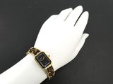 a woman ' s hand wearing a gold and black watch with a chain around it