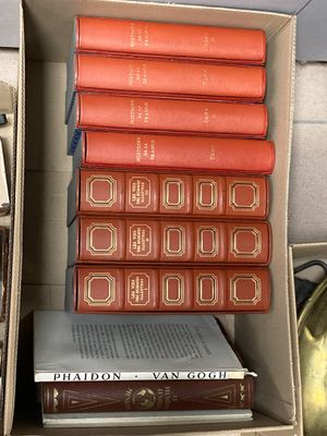 books are stacked in a cardboard box on a table