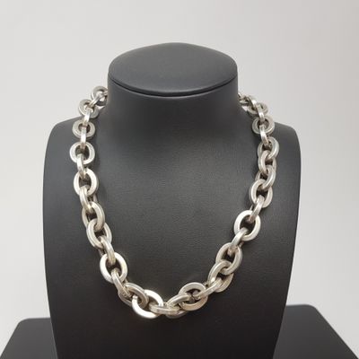 un gros plan sur un collier à chaîne en argent porté par un mannequin