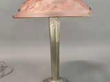 lamp with a pink shade sitting on a silver base with a white cord