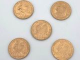 five gold coins are arranged in a row on a white surface