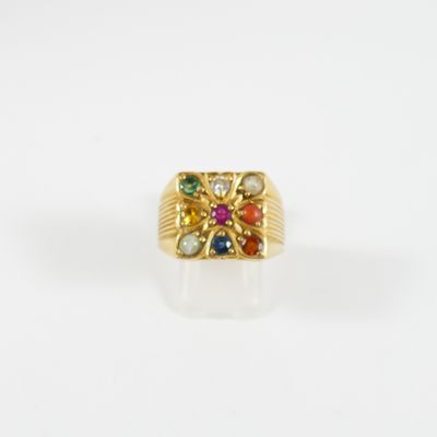 gros plan d'une bague en or avec des pierres multicolores