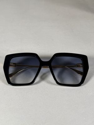 une paire de lunettes de soleil noires posée sur une surface blanche