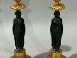 two black and gold candlesticks sitting next to each other on a white surface