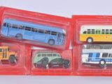 quatre petits bus de différentes couleurs dans un emballage rouge