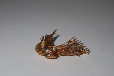 a gold bird brooch with a pearl in it