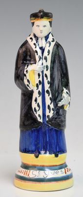 une figurine représentant un homme vêtu d'un manteau et d'un chapeau