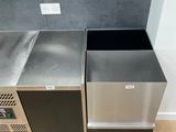 two trash bins in the corner of a kitchen