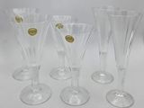 four clear wine glasses with gold rims on a white surface
