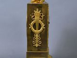 a gold clock with a statue on top of it