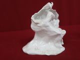 a white ceramic sculpture of a bird on a tree stump