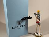 a figurine of a woman holding a bottle of wine next to a blue box