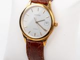 a gold wrist watch with a white dial on a brown leather band