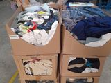 deux cartons sur lesquels sont posés des vêtements, dans un entrepôt
