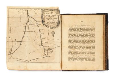 un livre ouvert, sur lequel figure une carte, posé sur une table