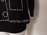 the back of a black sweater with white writing on it and a mannequin torso
